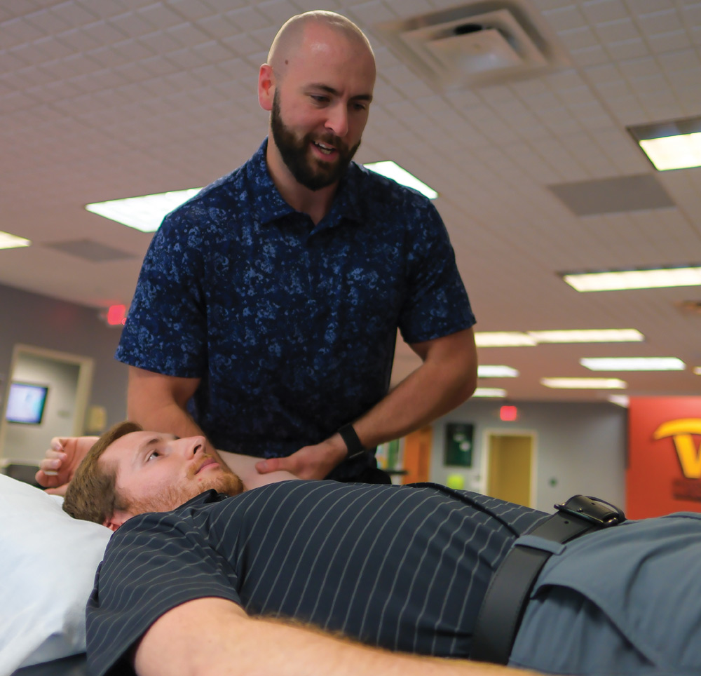 Jesse Phlegar performing physical therapy to a patient that is laying down