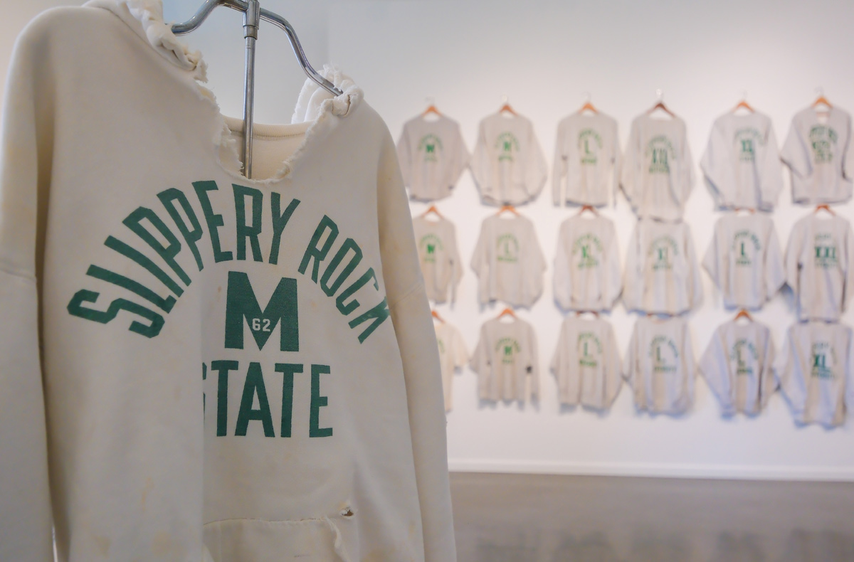 Slippery Rock State vintage hoodie with other ones on the wall behind it