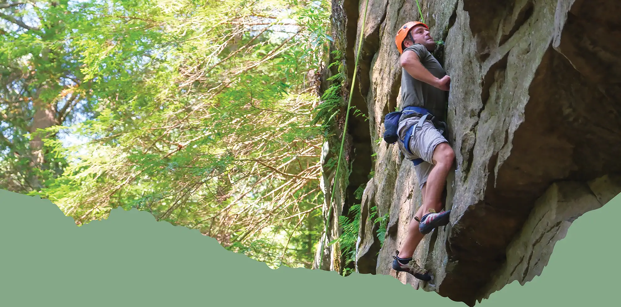 Sean Davis climbing cliff face during the day