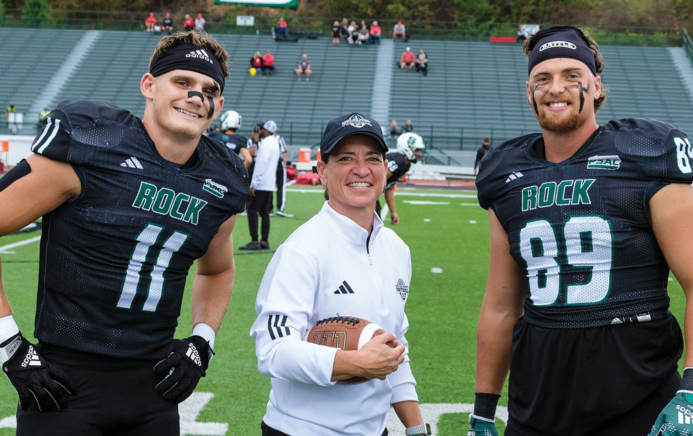 Lisa Horton on field with two Slippery Rock football players