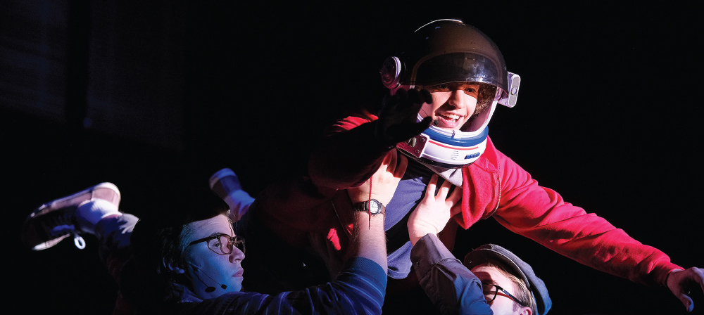 Conor McAleer in astronaut costume being held up by two others