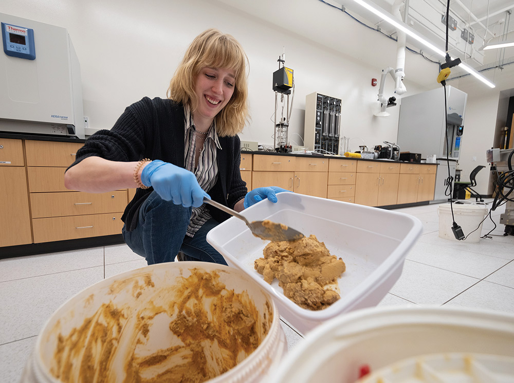 student Josephine Reott scoops acid mine sludge from an buckets, transferring the material into a smaller container