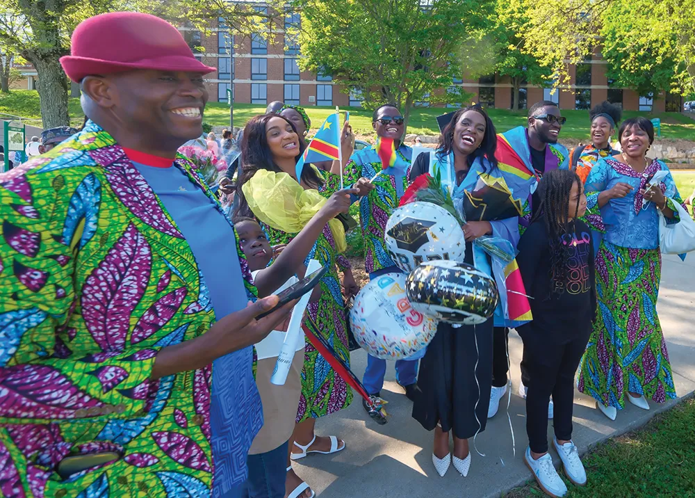 A joyful group of people in colorful clothing celebrating outdoors with flags and balloons.