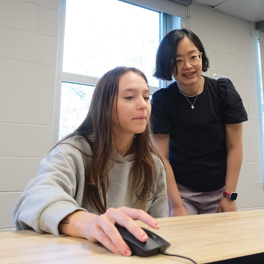 Xintong Wang helping a student working on a laptop