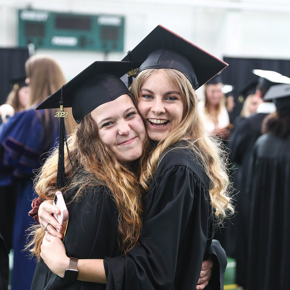 Ally Gilmore and Devin Parkinson hugging in their graduation cap and gown
