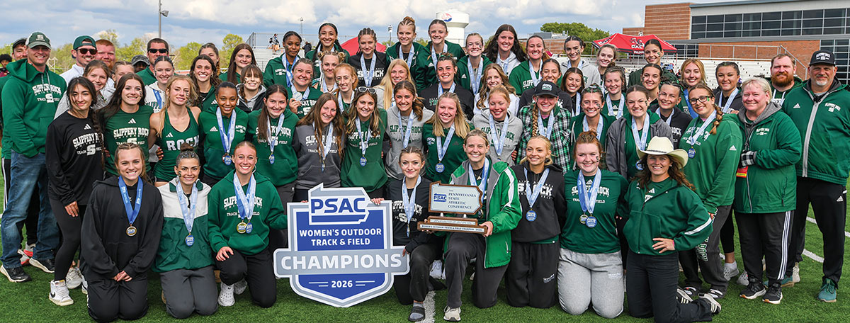 SRU's women's outdoor track and field team and their coaching staff celebrating a championship victory in a group picture on an outdoor turf field