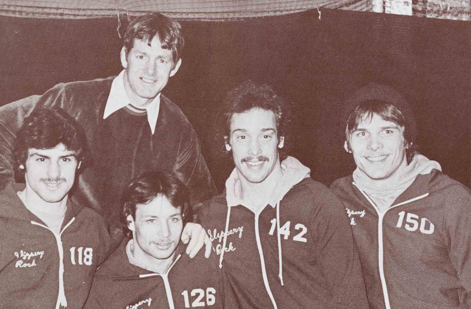 Vintage photo of four Slippery Rock University wrestlers and their coach in athletic jackets.