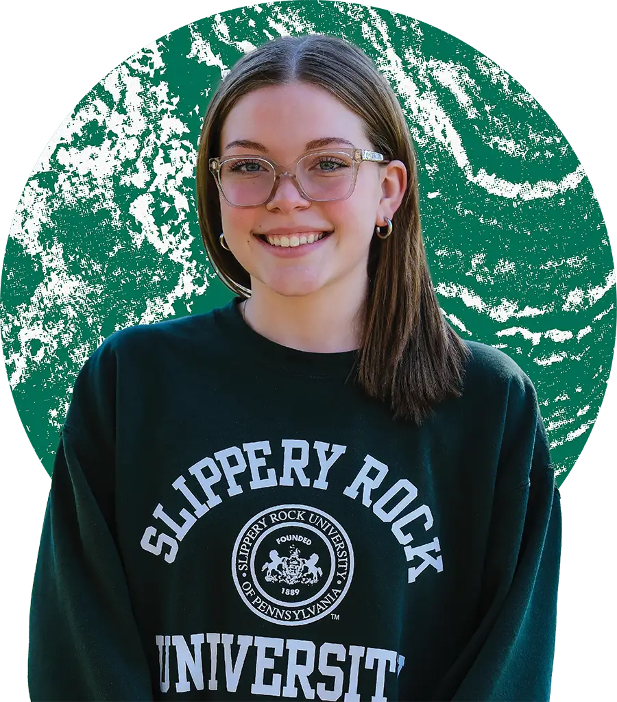 A smiling young woman wearing glasses and a dark green Slippery Rock University sweatshirt, framed by a textured green circular background.